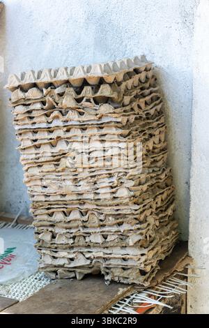 Stack of egg board is piled up against a wall. The boards are stacked on top of each other. Concept of organization and efficiency Stock Photo