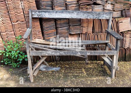 Bench is sitting in front of a pile of bricks. The bench is old and broken, and the pile of bricks is stacked on top of it. The scene gives off a sens Stock Photo