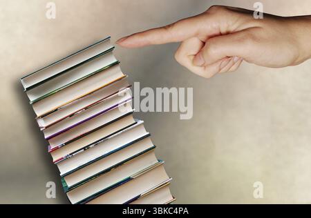 woman hand pushing a pile of books down Stock Photo