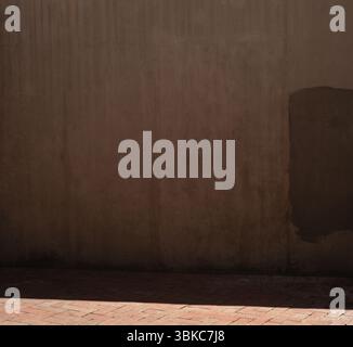Shadow falling on brick footpath against grunge brown wall, copy space Stock Photo