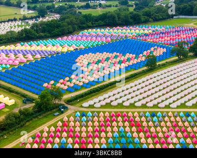 Worthy Farm, Pilton, Somerset, UK.  20th June 2025.  Aerial view of the colourful tents which have been erected in intricate patterns at the Worthy View camp site with a view across the music festival site ahead of the Glastonbury Festival at Pilton in Somerset which starts next week from the 25th June to 29th June 2025.  Picture Credit: Graham Hunt/Alamy Live News Stock Photo