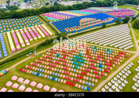 Worthy Farm, Pilton, Somerset, UK.  20th June 2025.  Aerial view of the colourful tents which have been erected in intricate patterns at the Worthy View camp site with a view across the music festival site ahead of the Glastonbury Festival at Pilton in Somerset which starts next week from the 25th June to 29th June 2025.  Picture Credit: Graham Hunt/Alamy Live News Stock Photo