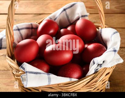 Traditional Greek Easter red dyed eggs in basket on wooden table Orthodox Easter symbol Stock Photo
