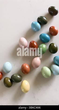 Assorted colorful eggs scattered on a light marble surface Stock Photo