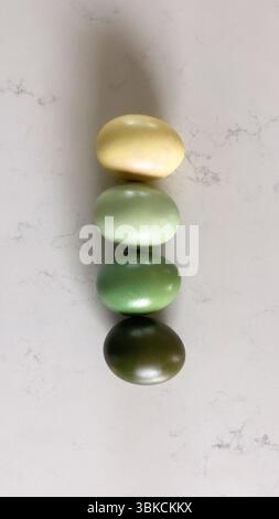 Four gradient-colored eggs in yellow and green stacked vertically Stock Photo