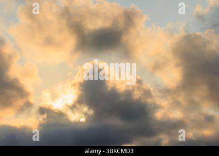 Cloudscape, Colored Clouds at Sunset over the sea on a Cloudy Day and sun behind the clouds Stock Photo