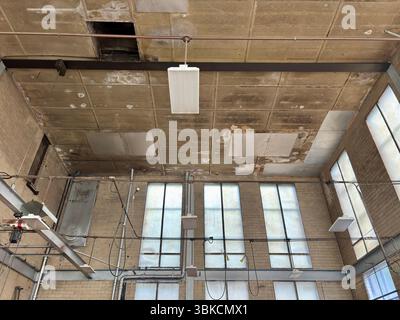 Tall windows, overhead lights, dirty ceiling in an old factory Stock Photo