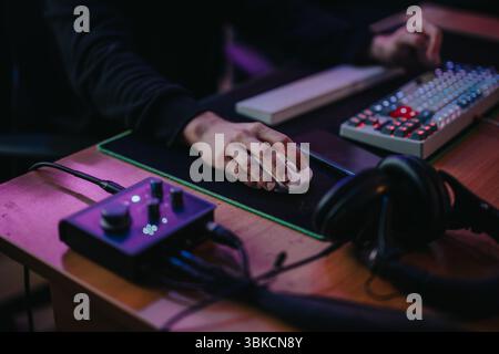Focused gaming setup with illuminated keyboard and audio controls in action Stock Photo