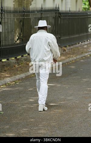 Man in White Suit and Hat Walking on an Urban Pathway. Greenwich, London, England Stock Photo