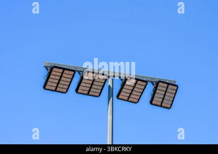 A tall pole with four lights on it. The lights are black and the Stock Photo