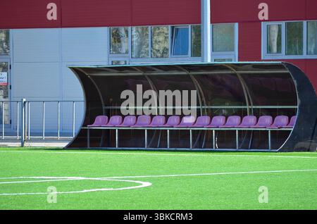 A row of pink chairs are lined up in front of a large, curved be Stock Photo