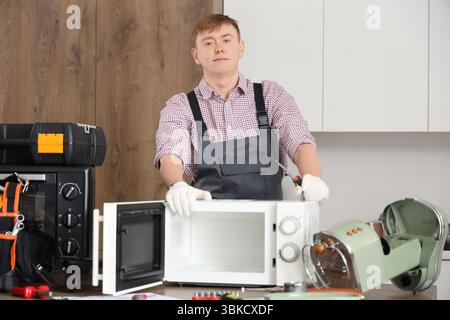 Male technician repairing microwave oven in kitchen Stock Photo
