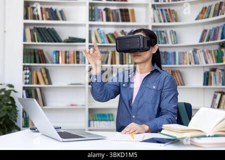 Woman in library wearing VR headset, interacting with virtual reality, using technology for learning and education. Stock Photo