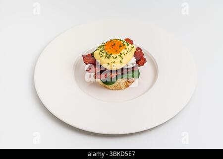 Eggs Benedict with poached egg, bacon, spinach and hollandaise sauce Stock Photo