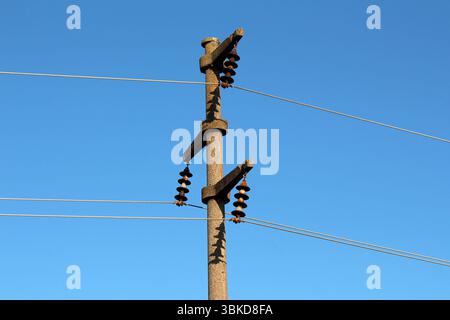 Concrete electric pole with ceramic insulators and voltage lines, in ...