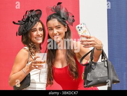 Ascot, Berkshire, UK. 20th June, 2025. Two young ladies pose for selfies at one of several large Union Jack flags. Racegoers arrive, mingle and pose for the opening day. Racegoers enjoy the beautiful sunshine on Royal Ascot Day 4 at Ascot Racecourse in Berkshire. Credit: Imageplotter/Alamy Live News Stock Photo
