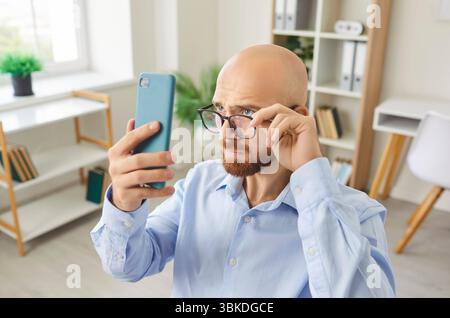 Surprised Man Browsing News On Smartphone While Working In Office Stock Photo