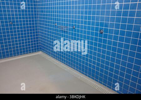 Corner of a Blue Tiled Public Shower Stall in a Fitness Center. Stock Photo