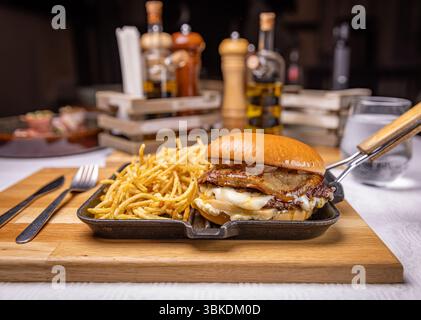 Delicious foie gras burger with matchstick fries served on hot pan in restaurant setting Stock Photo