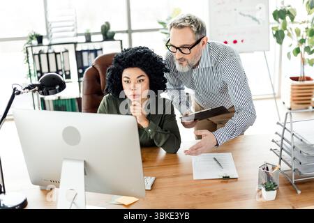 Office teamwork featuring a business meeting with a diverse group of professionals collaborating around a computer Stock Photo