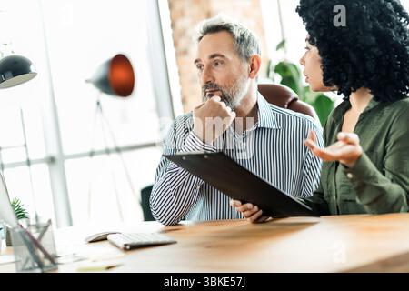 Professional business collaboration in a modern office setting, featuring diverse colleagues engaged in a work discussion Stock Photo