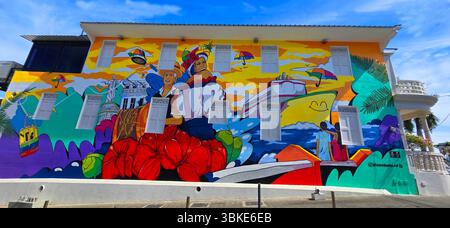 A very large colorful mural on the side of the wall of the building representing the culture and way of life in Puerto Plata Dominican Republic Taino Stock Photo