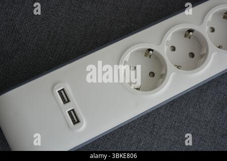 Things, electrical items. New stylish outlet, white stylish extension cords with powerful gray wire, two USB connectors are located on a gray fabric. Stock Photo