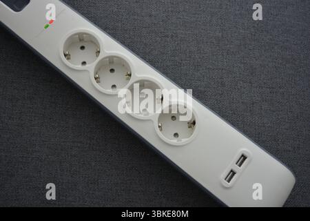 Things, electrical items. New stylish outlet, white stylish extension cords with powerful gray wire, two USB connectors are located on a gray fabric. Stock Photo