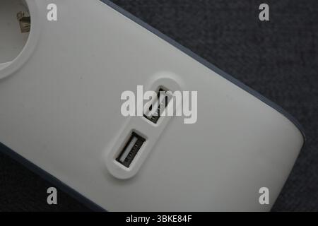 Things, electrical items. New stylish outlet, white stylish extension cords with powerful gray wire, two USB connectors are located on a gray fabric. Stock Photo