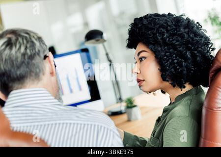 Two professionals collaborating in a modern office space focused on achieving goals and business strategies, showcasing teamwork Stock Photo