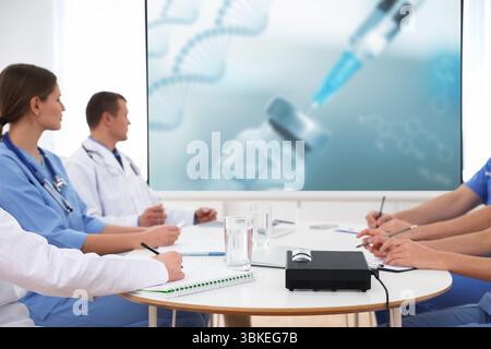 Team of doctors using video projector during conference about DNA indoors. Illustrations on projection screen Stock Photo