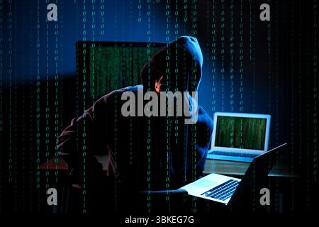 Cyber attack. Hacker working on computers in dark room. Binary code around him Stock Photo