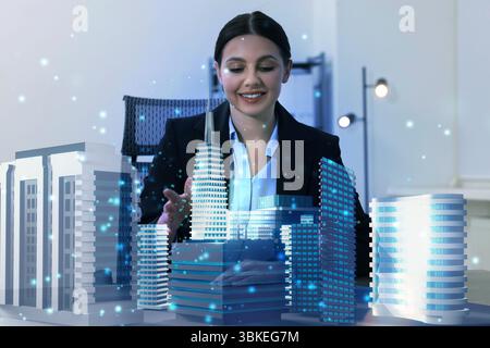 Building information modelling. Woman using holographic projection of city in office Stock Photo