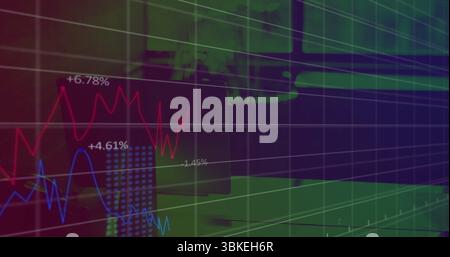 Displaying grid overlay and red blue line graph tracing trends at trading desk with monitor laptop Stock Photo