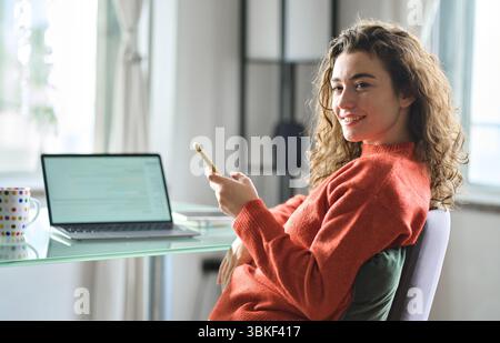 Young smiling pretty woman relaxing at home sitting at table. Candid photo Stock Photo