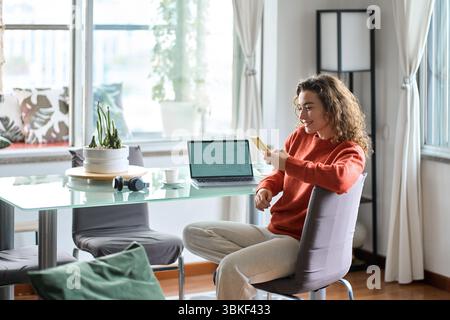Young smiling woman using mobile phone studying or working at home. Stock Photo