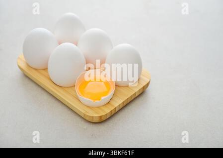 Eggs with white shell in wooden egg holder on light background closeup Stock Photo