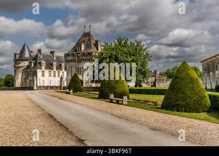 Château de la Roche Courbon in Saint-Porchaire: a view along the driveway towards the château, whose distinctive towers and slate roofs are typical of Loire Renaissance architecture. The château is still privately owned today; the gardens and parts of the château are open to the public. Château de la Roche Courbon on the Charente is now a popular tourist destination, particularly because of its famous French gardens. Rue de la Belle au Bois Dormant, Saint-Porchaire, Charente-Maritime, Nouvelle-Aquitaine, France Stock Photo