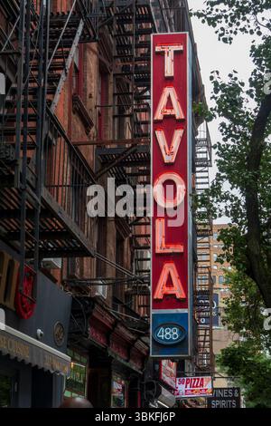 New York, NY - US - Jun 17, 2025 The iconic vertical red and white neon sign hanging above the Tavola Hells Kitchen, a casual Italian restaurant on th Stock Photo