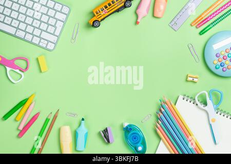 Back to school concept. Flat lay composition with Keyboard and school supplies on green background with copy space. Stock Photo