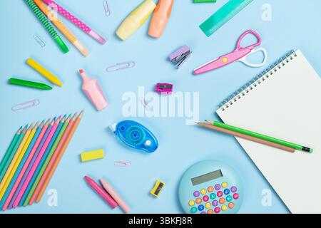 Colorful school supplies, calculator, scissors, notepad on light blue background. Back to school, education concept. Stock Photo