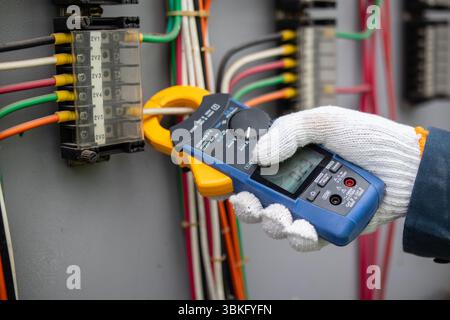 A staff member is working at power substation using multimeter to ensure electrical safety and efficiency Stock Photo