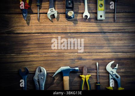 Hand tool collection is being displayed in flat-lay wood workbench, featuring hammer and wrenches Stock Photo