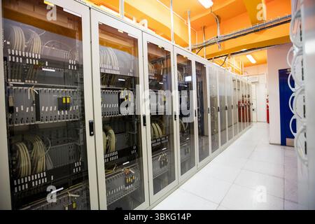 Flat design cabinets are lining data center corridor, showing patch cables, trays, tiles, lights Stock Photo