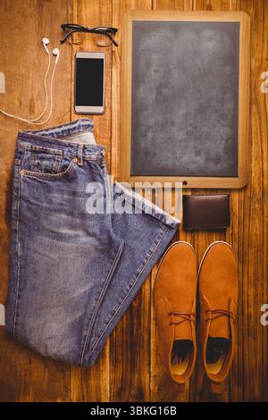 Showing flat design top-down with jeans boots chalkboard wallet phone and extras on wood tabletop Stock Photo