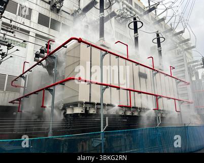 A testing fire extinguishing system on power transformer shows water mist surrounding equipment to ensure safety and prevent damage during operation i Stock Photo