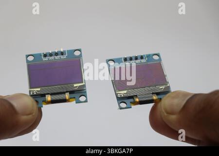 OLED screen with working and broken display held in the hand side by side on a white background Stock Photo