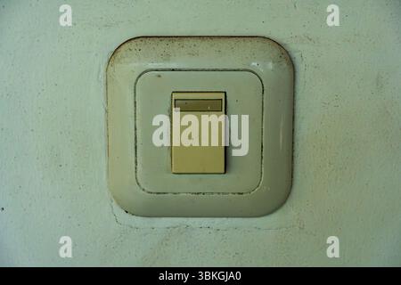 White switch on a wall. The switch is dirty and has a white cap Stock Photo