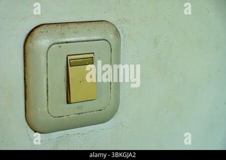 White switch on a wall. The switch is dirty and has a white cap Stock Photo