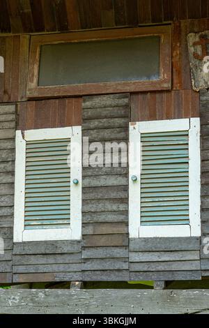 Two windows with green and white shutters. The shutters are open and the windows are closed Stock Photo